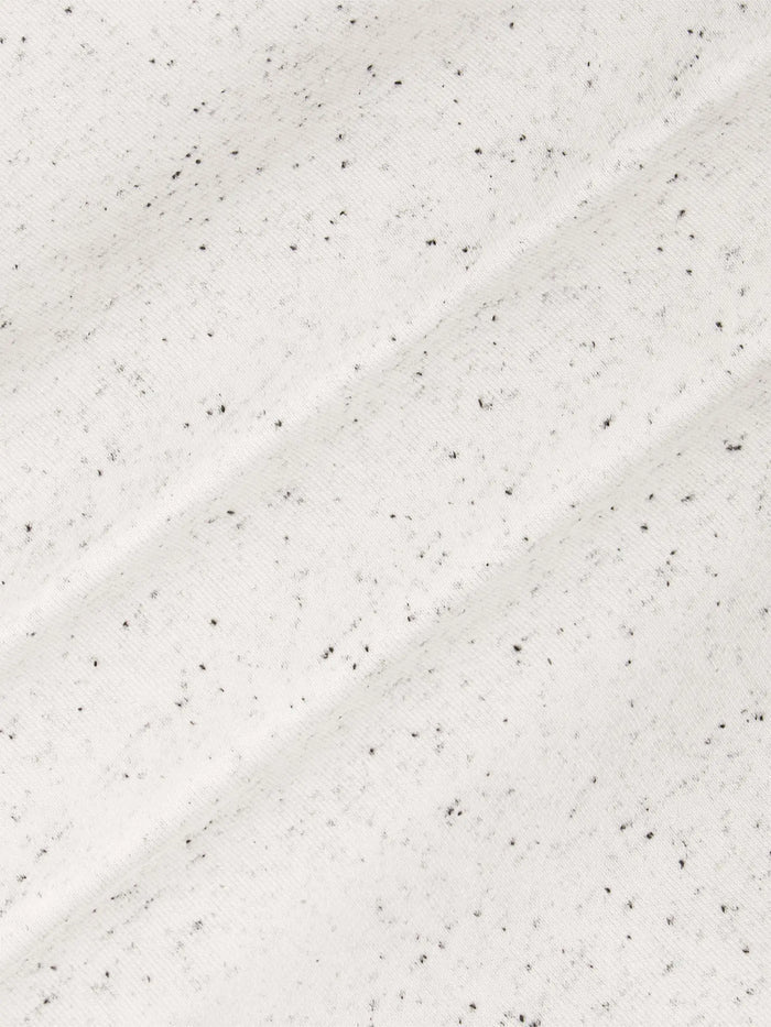 Close-up of a textured white surface with small black specks