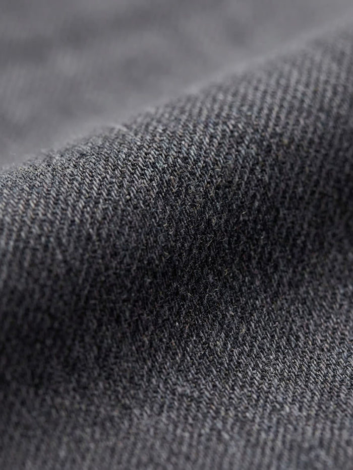 Close-up of grey denim fabric texture with fine weave detail.