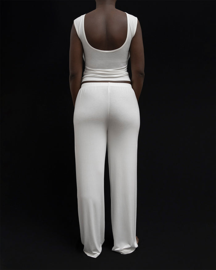 Back view of a model in Kye Recline Pant bamboo long pants in white. The pants feature a comfortable elastic waistband and are made from soft, eco-friendly bamboo fabric, highlighting the quality of Kye Intimates.
