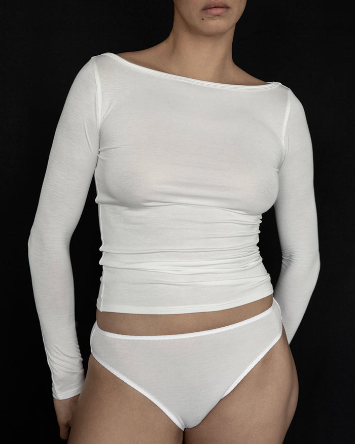 Model wearing Kye Recline Bateau Long Sleeve, a white bamboo boat neckline long sleeve tee, paired with matching white briefs.