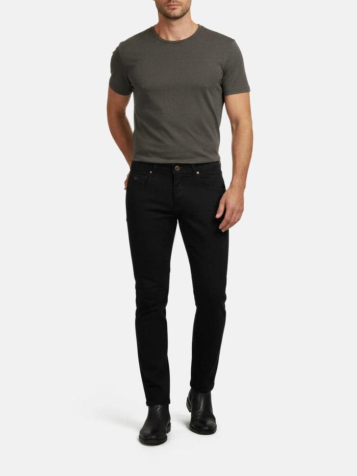 Full-body view of a man wearing black slim-fit jeans styled with a basic t-shirt.