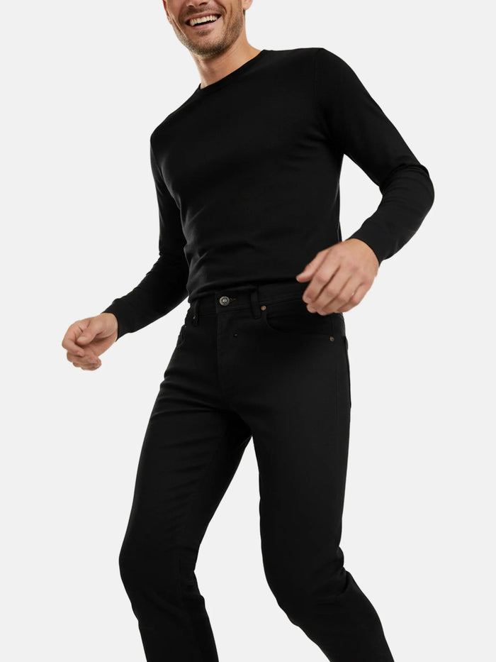 Close-up of a man wearing black slim-fit jeans paired with a black long-sleeve top.