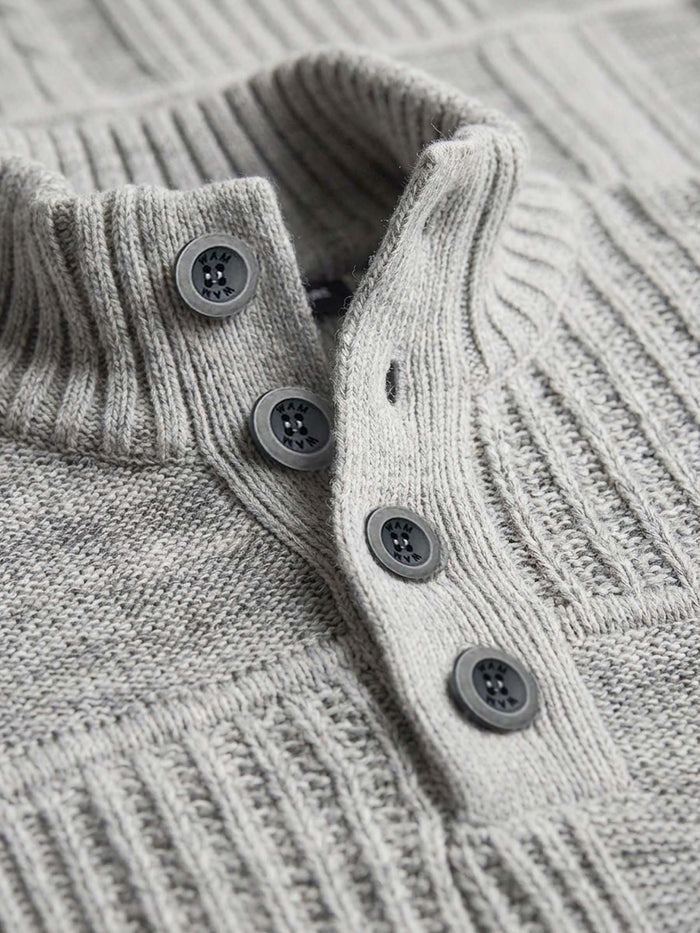 Close-up of light grey knit sweater’s ribbed collar and button placket detailing.