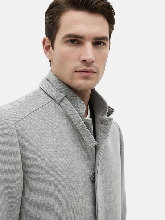 Close-up of grey trenchcoat collar showcasing textured fabric and button details.