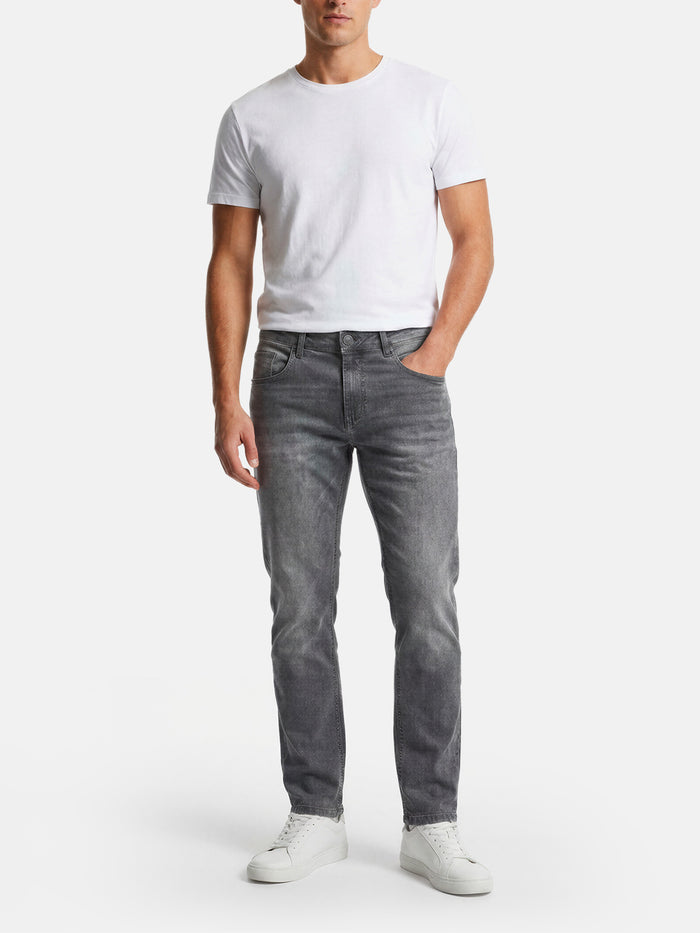 Model wearing slim-fit grey jeans styled with a white t-shirt and sneakers.