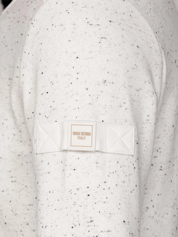 Speckled Off White sweater with a brand label on a matching background