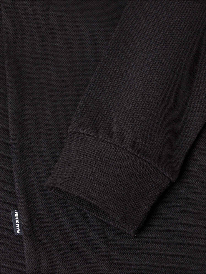 Close-up of black sweater sleeve with ribbed cuff and woven texture detail – Wam Denim.