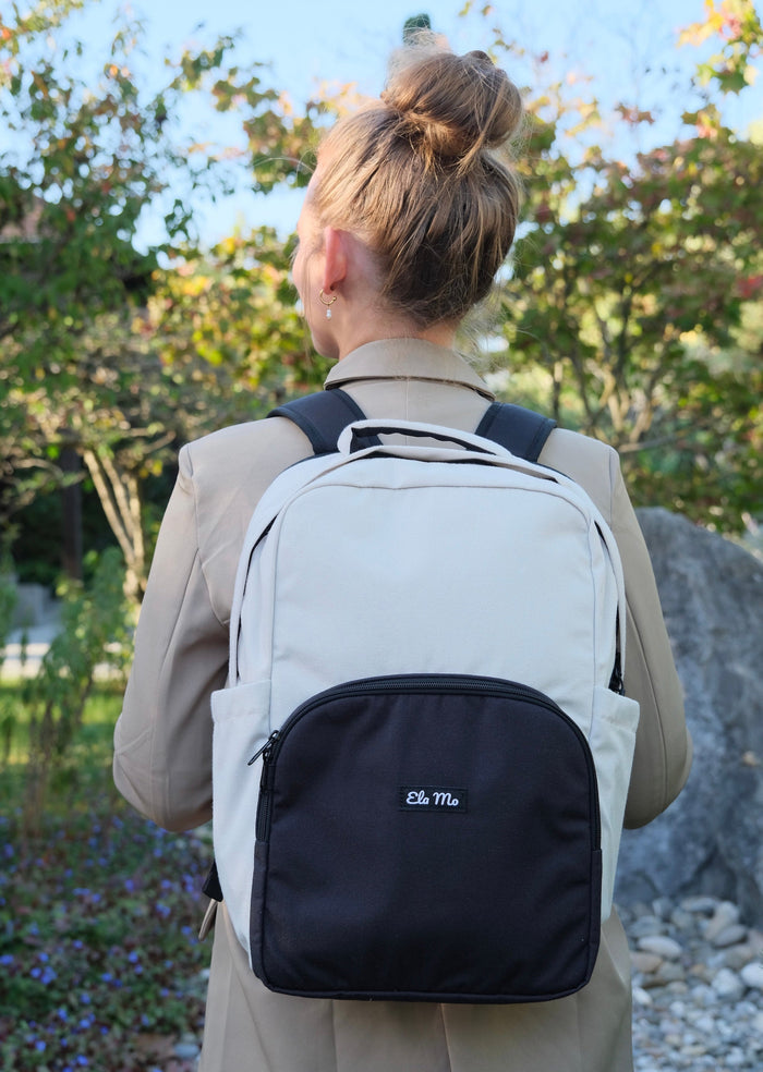Ela Mo™ Work Rucksack | Desert. Ein Mädchen mit dem grauen Schulrucksack auf der Straße.“