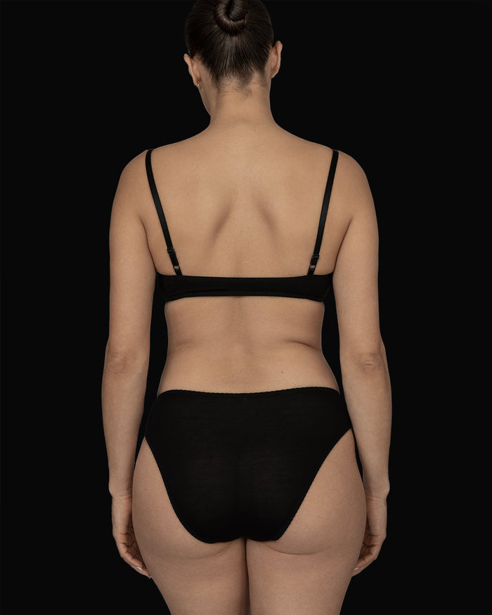 Back view of a model wearing Kye Recline Bra, featuring the black bamboo pull-over scoop neck bralette.