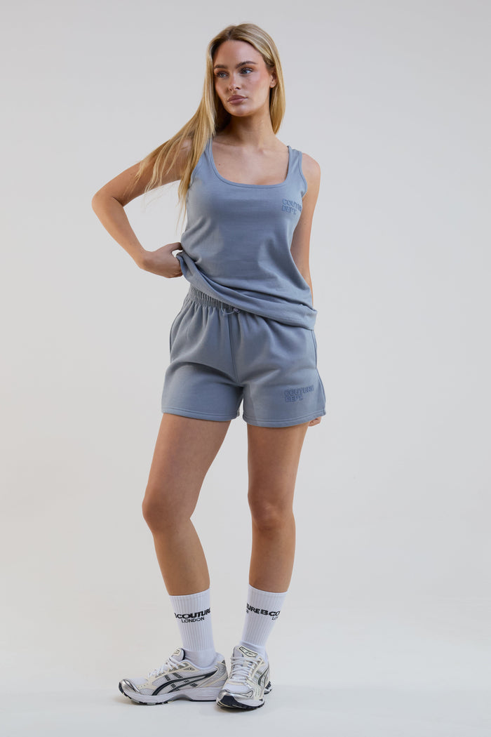 Woman wearing a blue athletic outfit with white socks on a plain background