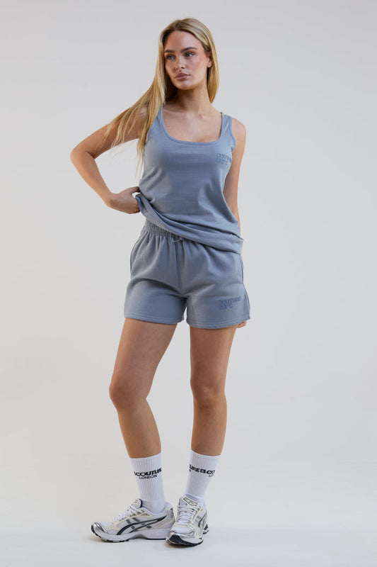 Woman wearing a blue athletic outfit with white socks on a plain background